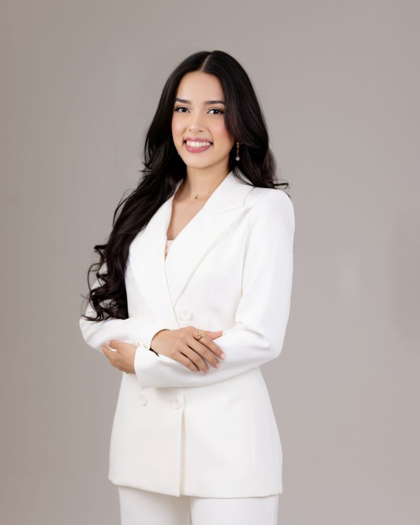 Retrato profesional de Adriana Castellón, fundadora de Alma Marketing Studio, con un atuendo blanco profesional y las manos cruzadas.